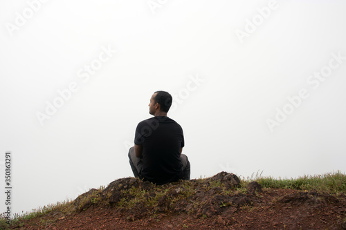 man isolated feeling the serene nature at hill top with amazing cloud layers in foreground photo