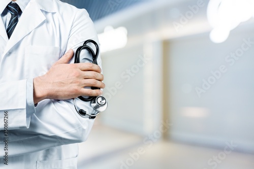 Young man doctor holding stethoscope on background