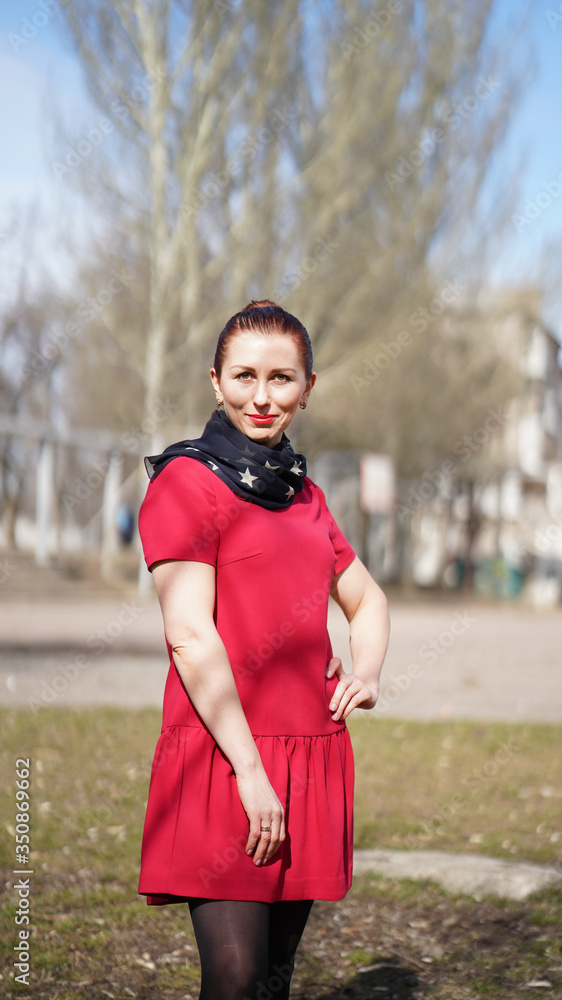 Naklejka premium Beautiful smiling woman in red dress in a park in spring