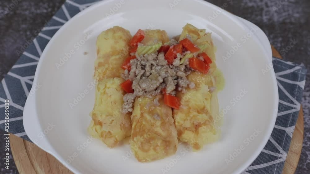 Pouring gravy sauce and sprinkle cabbages on top Deep Fried Tofu in a white plate , rotating on a white plate Pouring gravy sauce and sprinkle cabbages on top Deep Fried Tofu in a white plate , rotating on a white plate