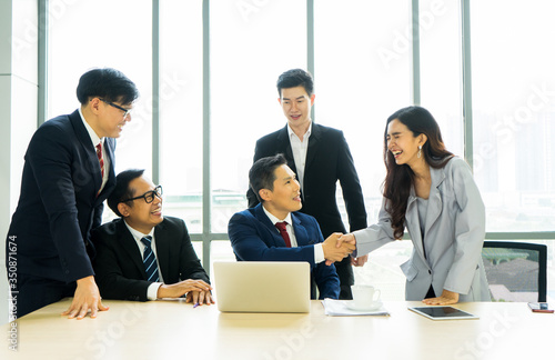 Asian business male and female smiling shake hands with congratulation. Acquainted during business meeting, coworkers greeting introducing.