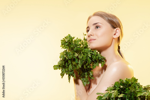 Close up of beautiful young woman with green leaves on white background. Concept of cosmetics, makeup, natural and eco treatment, skin care. Shiny and healthy skin, fashion, healthcare.