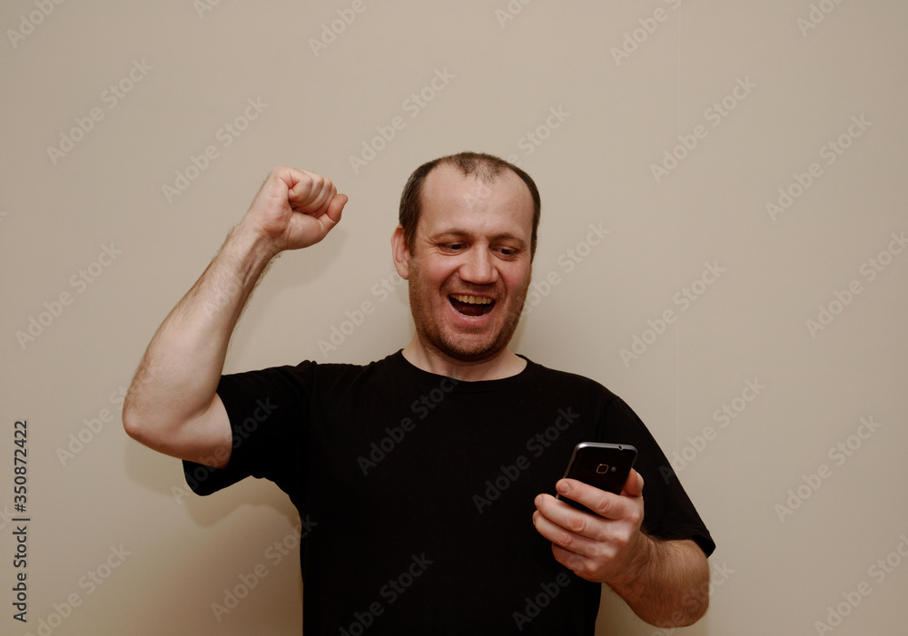 the man enthusiastically raised his right hand while looking at the smartphone. the man enthusiastically raised his right hand while looking at the smartphone.