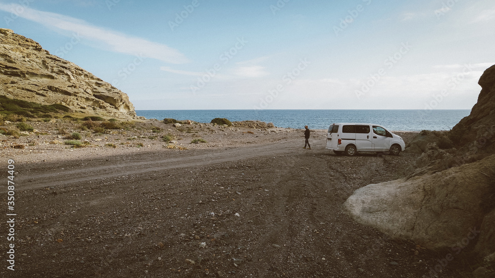 Furgoneta camper con hombre en una playa de Almería con el mar de fondo en un día despejado Furgoneta camper con hombre en una playa de Almería con el mar de fondo en un día despejado