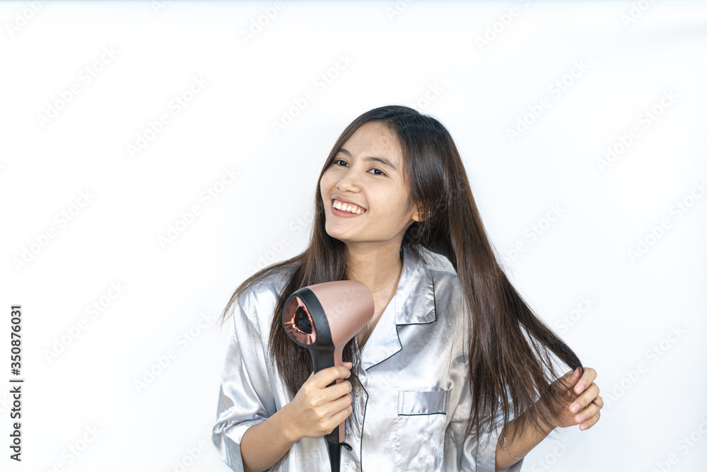 A beautiful Asian girl is using a hairdryer with sleepwear. A beautiful Asian girl is using a hairdryer with sleepwear.