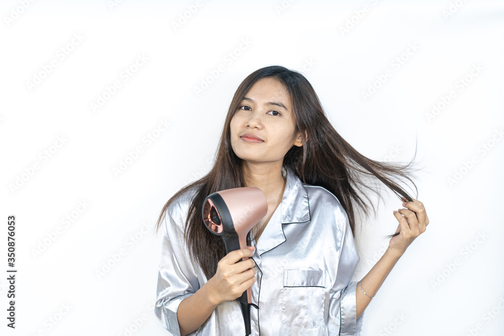 A beautiful Asian girl is using a hairdryer with sleepwear. A beautiful Asian girl is using a hairdryer with sleepwear.