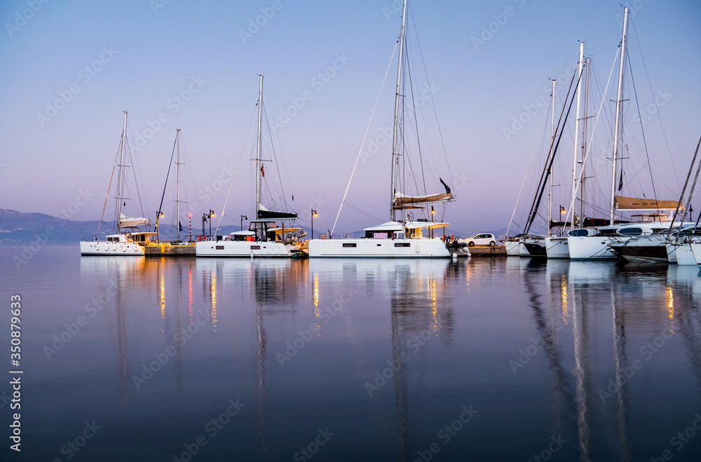Yachts in the harbor at dawn. Beautiful reflection. Nature background. Concept of silence, relax and tranquility. Luxury lifestyle.