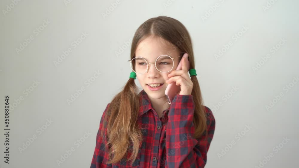 Cute teen girl talking by mobile phone near white wall Cute teen girl talking by mobile phone near white wall