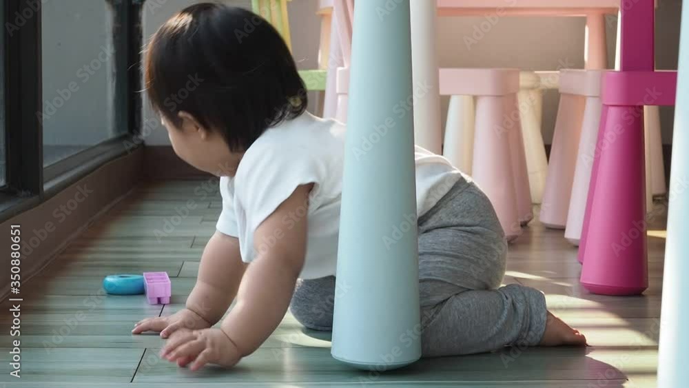 Asian infant baby girl is playing under the table and crawling away.
Asian infant baby girl is playing under the table and crawling away.