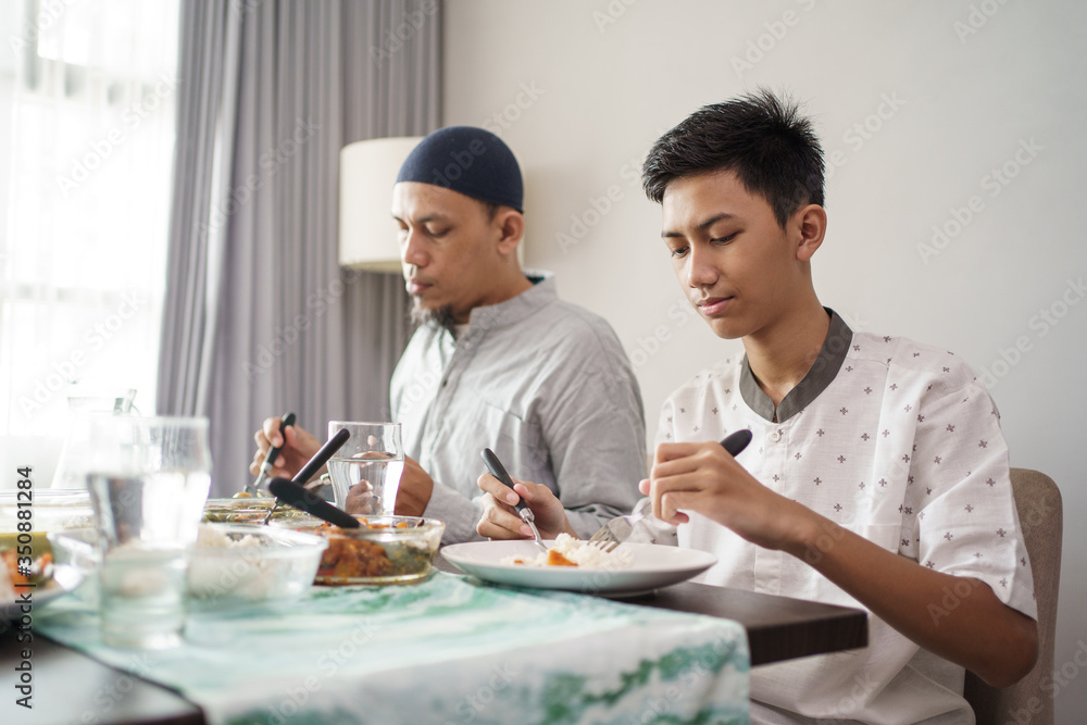 muslim father and son eating some dinner together at home