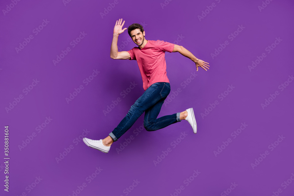 Full size photo of cheerful excited enthusiastic guy jump see his friend wave hand say hello wear good look outfit isolated over vivid color background