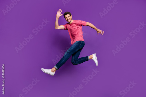 Full size photo of cheerful excited enthusiastic guy jump see his friend wave hand say hello wear good look outfit isolated over vivid color background