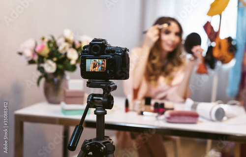 Famous blogger at home. Young attractive woman fashion vlogger talking to the camera about make up and cosmetics while recording a beauty vlog. Blogging as a lifestyle of modern women.