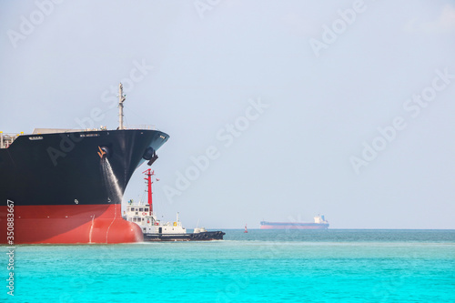 Side Cargo ship in the sea with tugboat assistance go to the port fixed rope on the front of Bulbous bow ship Logistics and Transportation of international Container Cargo ship.