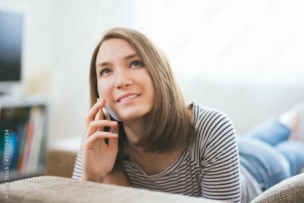Beautiful young caucasian woman on sofa using cell phone Beautiful young caucasian woman on sofa using cell phone