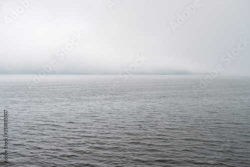 Clouds fog over mountain lake Beratan in Bali. The calm expanse of water under thick clouds