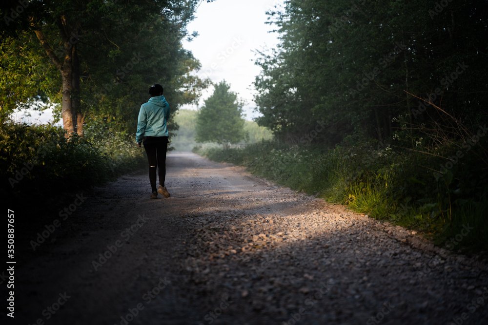 Fototapeta premium A young woman is walking on dusty countryside road alone