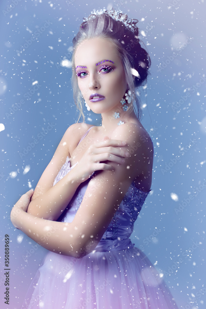 Girl model in the image of the snow queen on a background of snow .Winter girl.