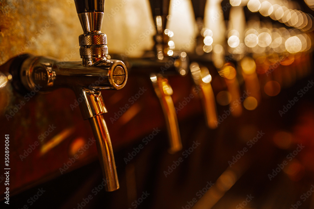 Details of the beer bar. Beer taps in a row in perspective. Warm tinting, different focus. Close up of beer Tap. Selective focus.