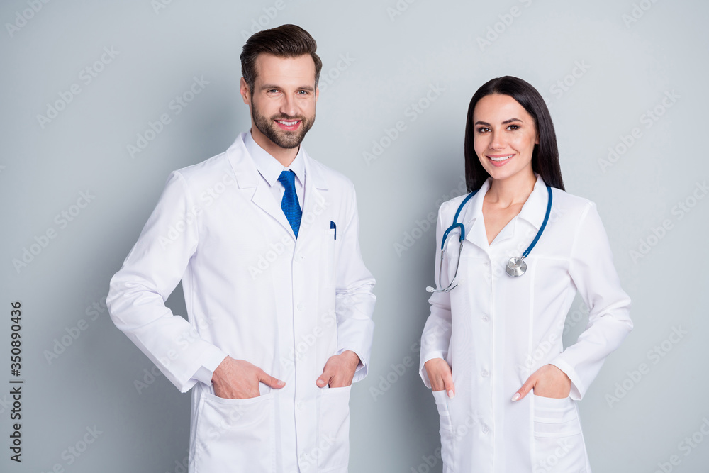 Photo of handsome doc guy practitioner experienced professional pretty lady two people patients consultation virology clinic good mood wear lab coats isolated grey color background Photo of handsome doc guy practitioner experienced professional pretty lady two people patients consultation virology clinic good mood wear lab coats isolated grey color background