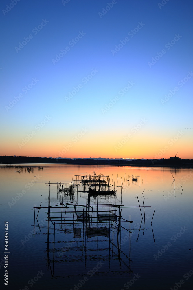 Fish trap and calm blue lake at dawn