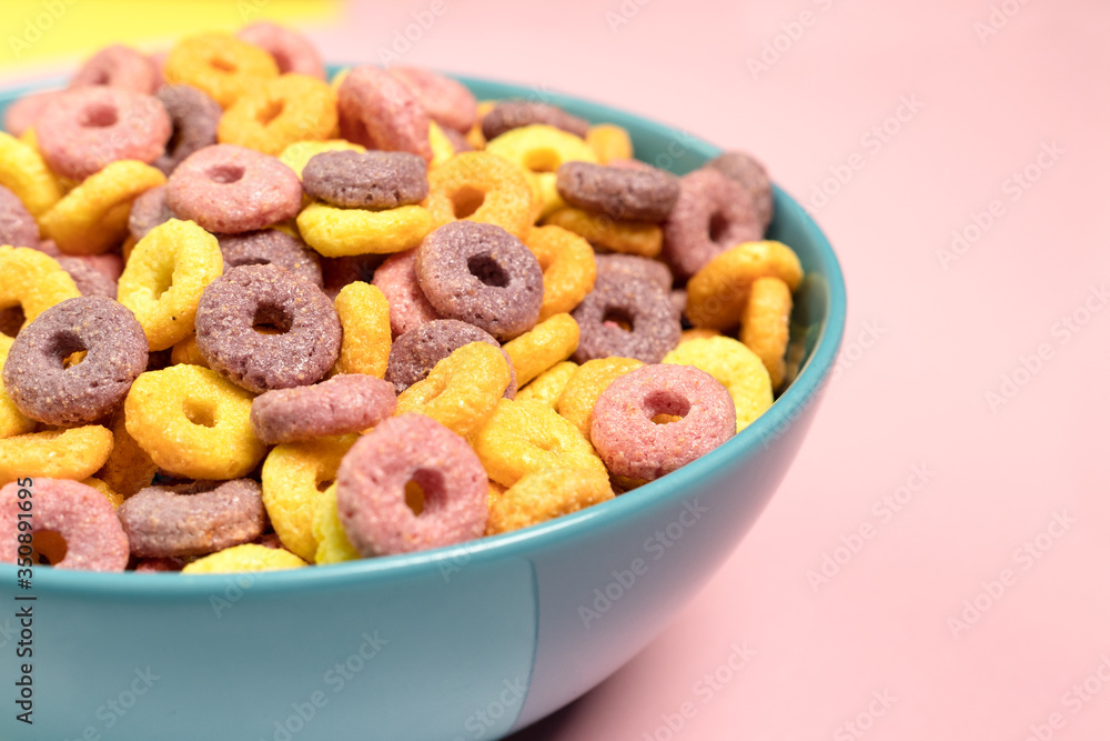 Breakfast with Colorful cereals in blue bowl and pink background Breakfast with Colorful cereals in blue bowl and pink background