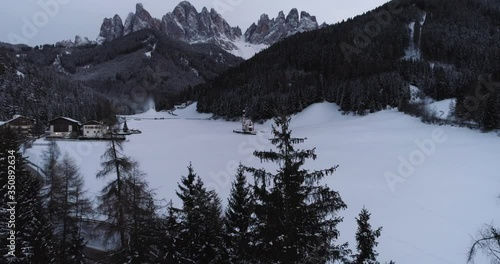 Fly through trees reveals church in Val Di Funes, Italy Dolomites
