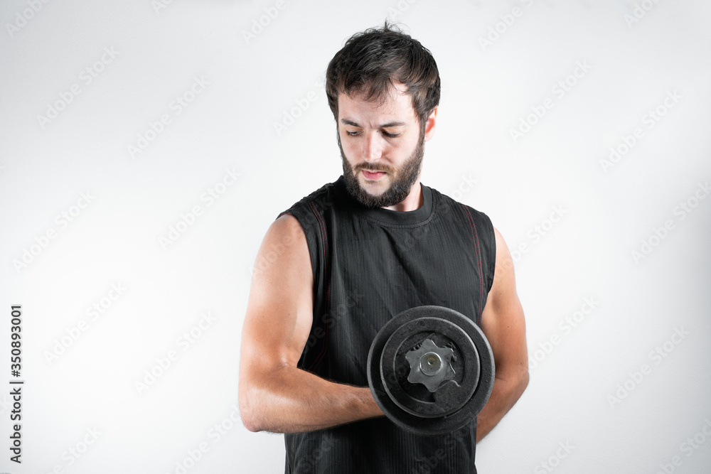 Young and handsome man with a beard in fitness session, lifting weights or dumbbells, exercising the biceps muscle. On a white background.
