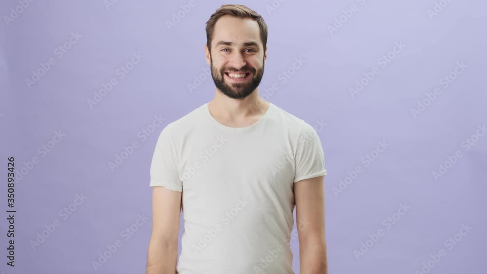 A cheerful excited man wearing white t-shirt is laughing celebrating success standing isolated over gray background A cheerful excited man wearing white t-shirt is laughing celebrating success standing isolated over gray background
