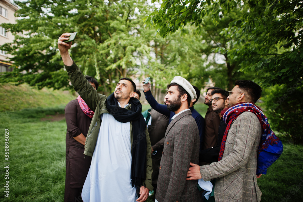 Group of pakistani man wearing traditional clothes salwar kameez or kurta making selfie on mobile phone.