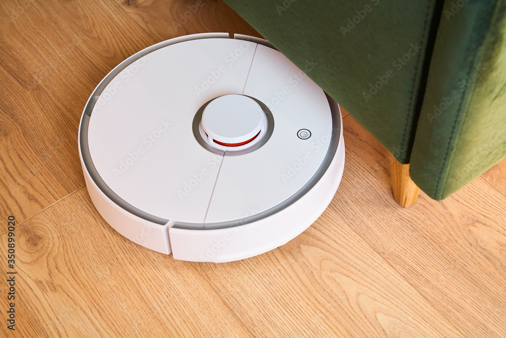 modern automatic vacuum cleaner washing floor near green sofa modern automatic vacuum cleaner washing floor near green sofa