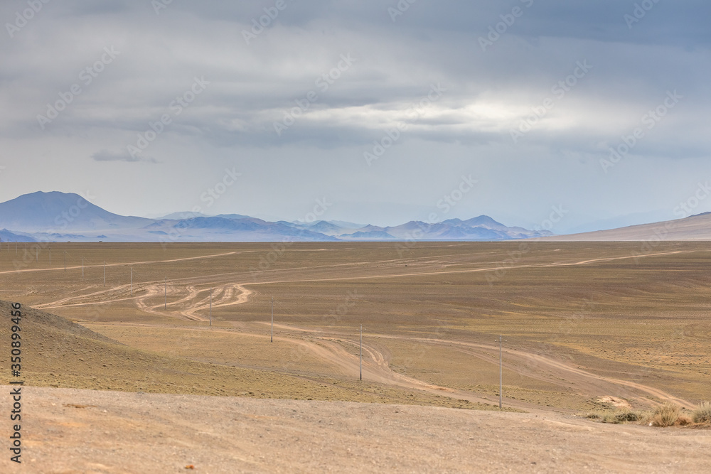Typical view of Mongolian landscape. Winding dirt road through lush rolling hills of Central Mongolian steppe. Mongolian Altai