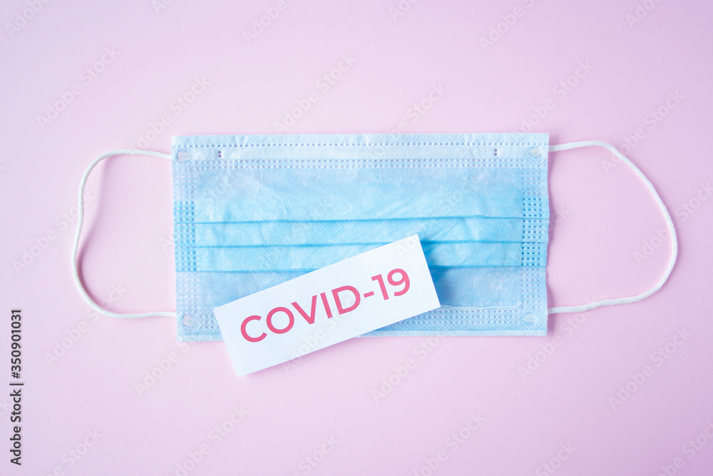 The inscription quote covid-19 on a medical mask on pink background. Coronavirus treatment concept. Medicines, vaccine for the virus. The inscription quote covid-19 on a medical mask on pink background. Coronavirus treatment concept. Medicines, vaccine for the virus.