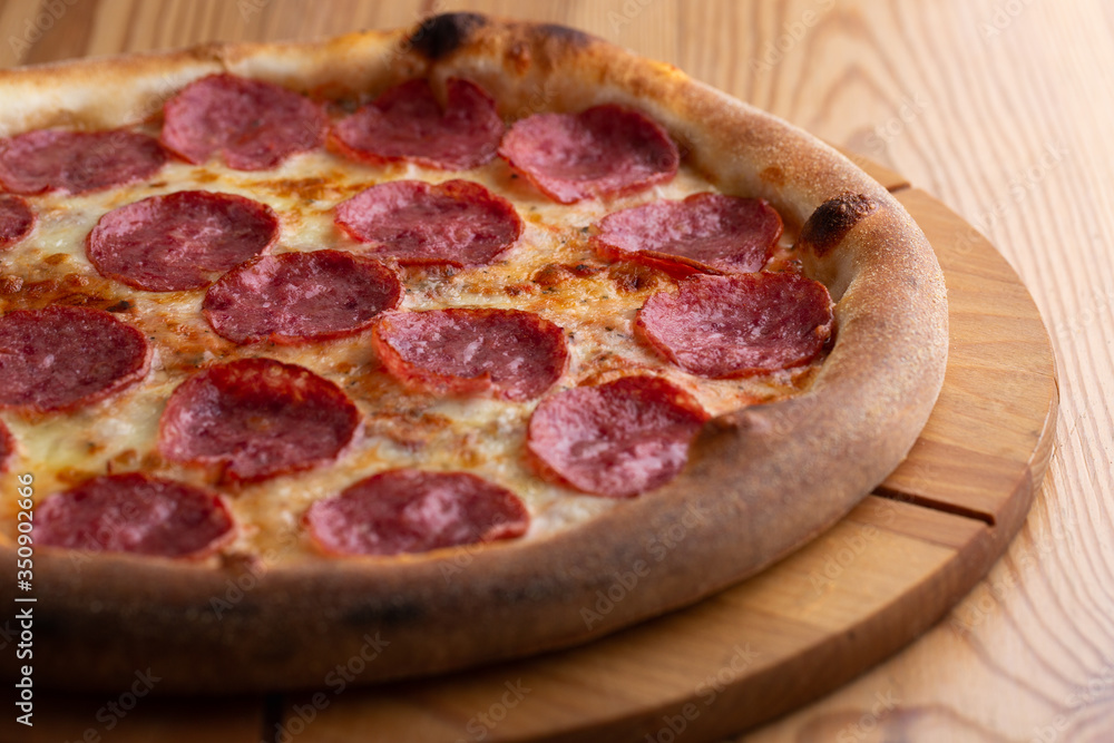 hearty italian pizza on a wooden board. cheese pizza with salami sausage hearty italian pizza on a wooden board. cheese pizza with salami sausage