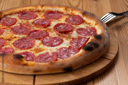 hearty italian pizza on a wooden board. cheese pizza with salami sausage