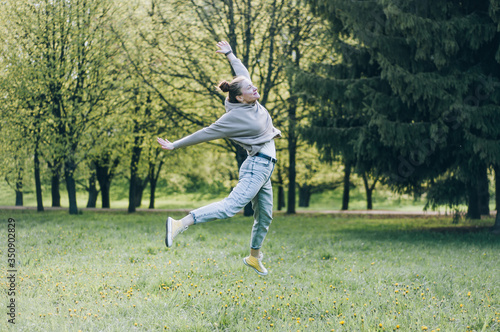 Girl dancing near the lake, sunny weather. A young woman rejoices in life, dances and sings. She has a good mood and a smile on her face.