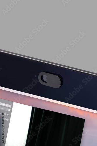 Detailed shot of a black webcam cover fixed on a laptop camera. The anti-spy slider made for your privacy and security is in open position. 