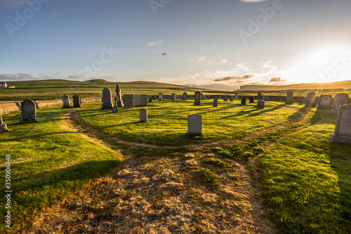 old hillswick cemetery full of tombstones on the Shetland (Scotland, UK) on a panoramic sunset with dramatic warm light and illuminated green grass