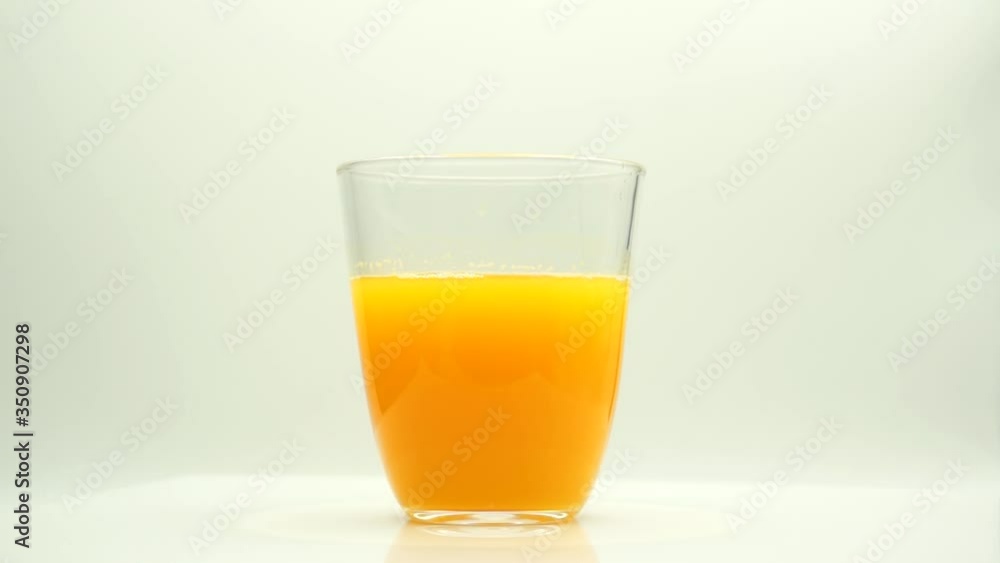 Vaso de zumo de naranja girando sobre fondo blanco Vaso de zumo de naranja girando sobre fondo blanco
