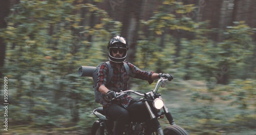 Young rider driving motorcycle on forest road