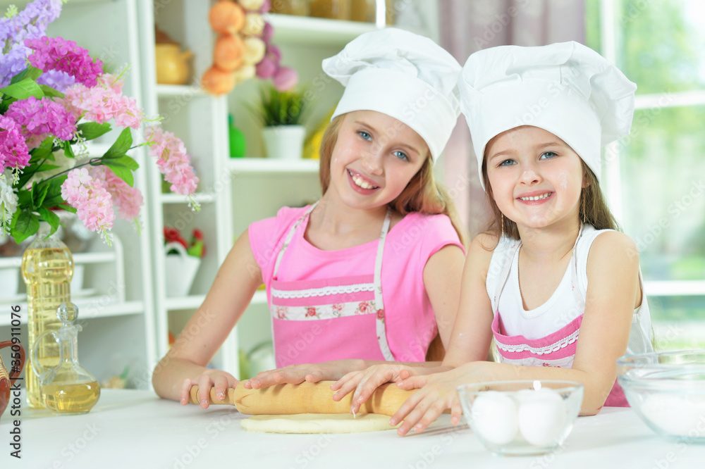 Cute little girls in chefs hats making dough Cute little girls in chefs hats making dough