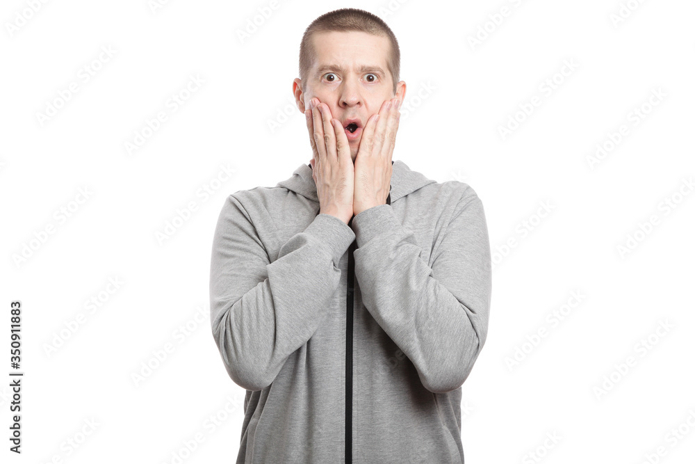 astonished man admires luck and victory, opened his mouth and grabbed both hands by the cheeks, dressed in a gray jacket. A look into the camera. Isolated astonished man admires luck and victory, opened his mouth and grabbed both hands by the cheeks, dressed in a gray jacket. A look into the camera. Isolated
