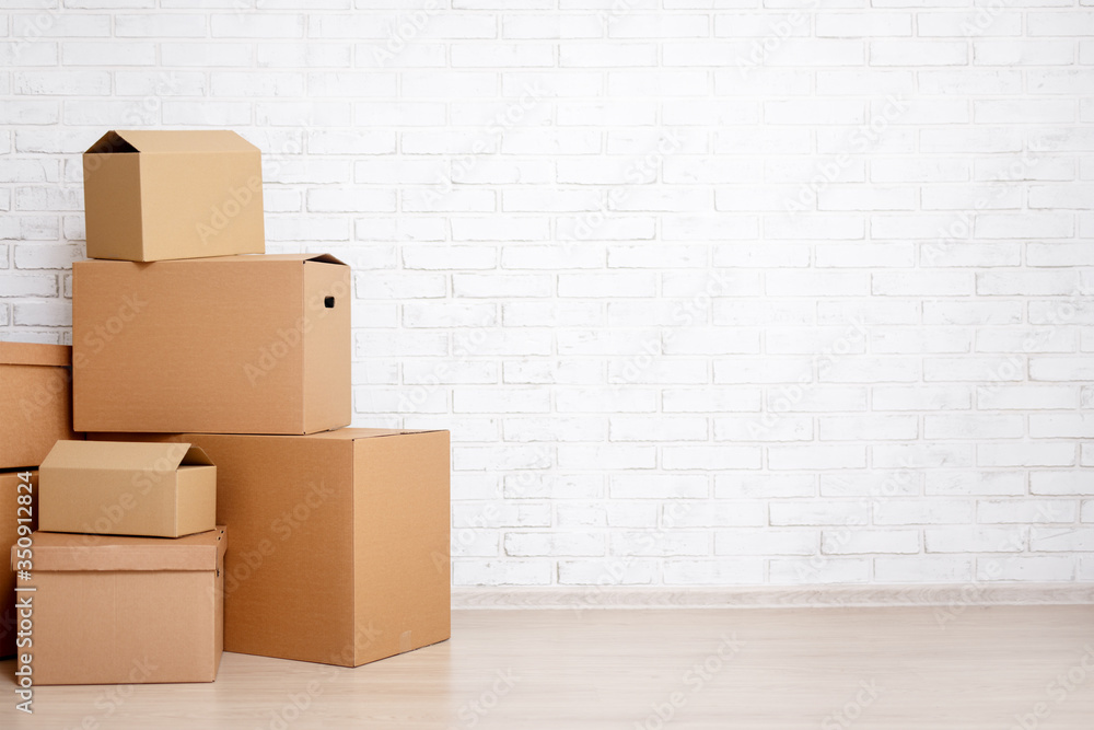 moving day concept - cardboard boxes and copy space over white brick wall - obrazy, fototapety, plakaty 