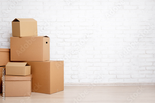 moving day concept - cardboard boxes and copy space over white brick wall