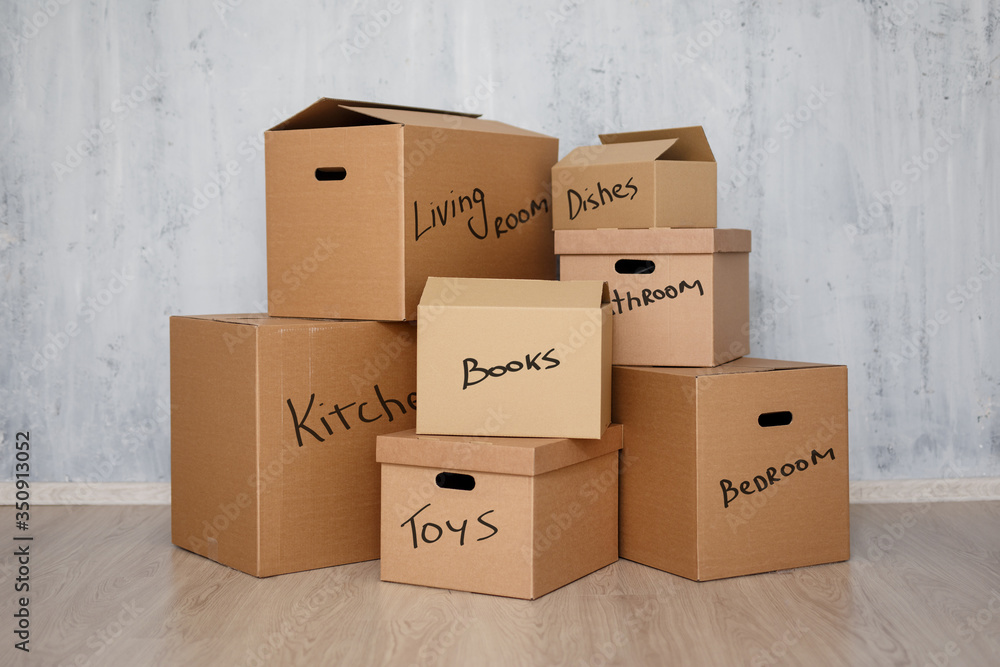 moving day - brown cardboard boxes with belongings stacked over gray background - obrazy, fototapety, plakaty 