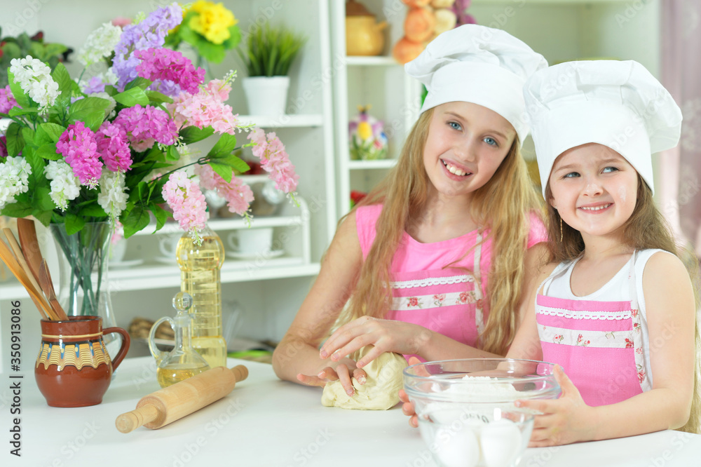 Cute little girls in chefs hats making dough Cute little girls in chefs hats making dough