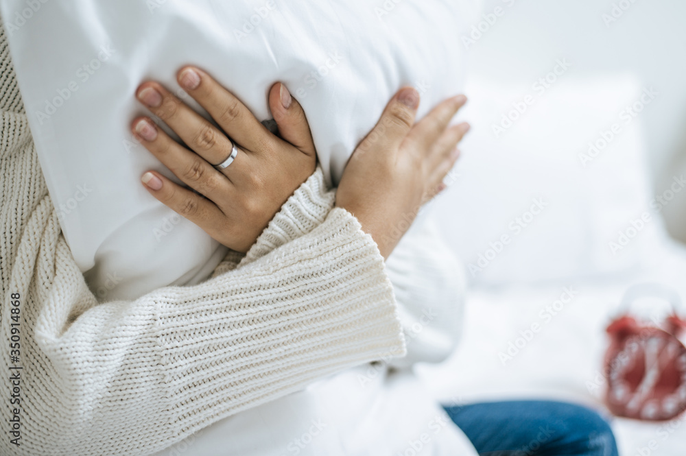 Cross hands and sit, hug a white pillow on the bed. Cross hands and sit, hug a white pillow on the bed.