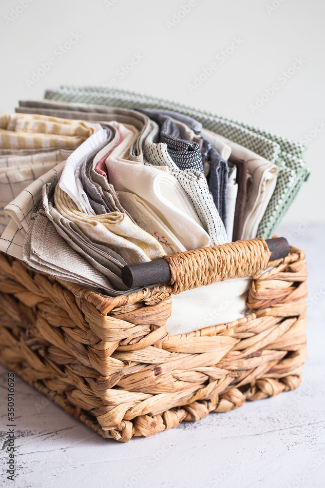 Obraz premium kitchen textile. stack of fabrics in different colors and textures, close-up. Kitchen towels on white background. Many fabric kitchen napkins in a wicker basket. Props for foodphotography
