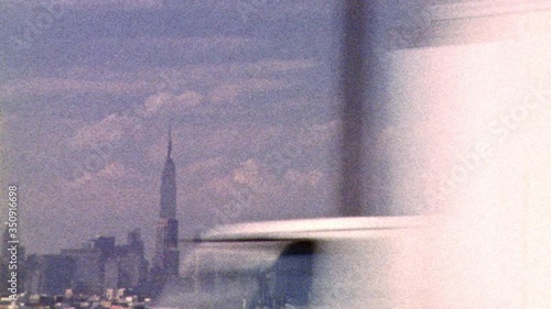 Vintage looking archival footage filmed in New York City driving on highway with city skyline in the distance and Empire State Building