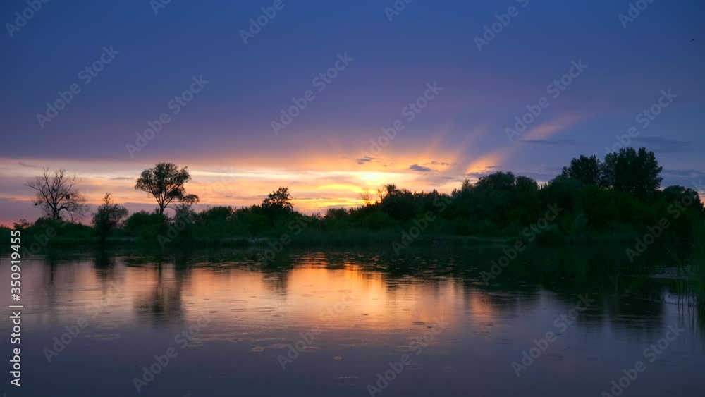 Scenic Sunset Reflection on River Raindrops on Water Surface. Evening Countryside Rural Scenery. Rainy Clouds Weather Spring season Scenic Sunset Reflection on River Raindrops on Water Surface. Evening Countryside Rural Scenery. Rainy Clouds Weather Spring season